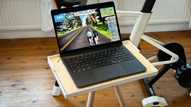 Laptop on the wooden stand in front of a turbo trainer, training app on screen