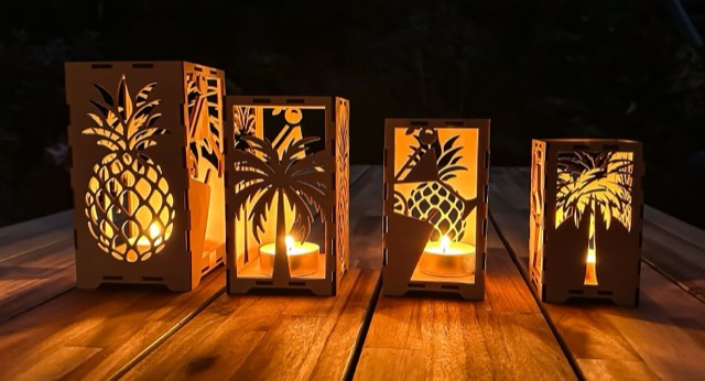 Wooden lanterns with pineapple and palm-tree motifs, tealights burning inside